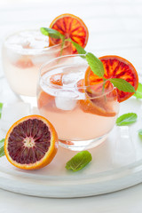 Blood orange cocktail with slices of orange on white wooden background