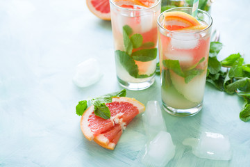 Refreshment grapefruit cocktail with mint on mint color background. Healthy citrus summer drink.