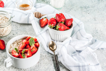 Healthy summer breakfast, overnight oatmeal with fresh strawberry and milk, grey stone background