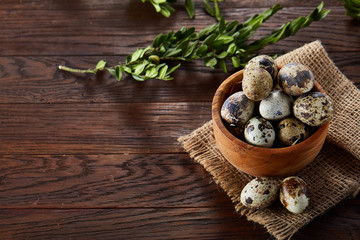 Bowl with eggs quail, eggs on a homespun napkin, boxwood on wooden background, close-up, selective focus, top view