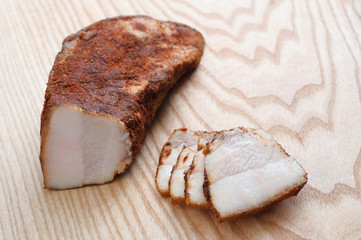 Tasty smoked pork ham with spices. Cut in slices on a wooden background