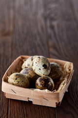 Quail eggs in a box on a rustic wooden background, top view, selective focus, vertical