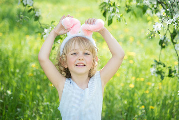 Cute funny girl with Easter eggs and bunny ears at garden. easter concept.