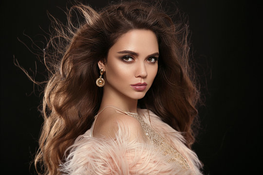 Brunette in fashion fur coat. Beauty portrait of gorgeous sexy brunette woman with long healthy hair and evening makeup isolated on black background. Fashionable girl portrait. Vogue style.