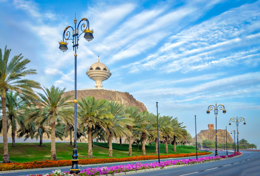 Stylish Streetlights, palm trees and roadside flower beds with the frankincense burner monument in the background.