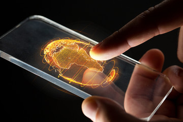 business, globalization and future technology concept - close up of businessman hands with transparent smartphone and earth hologram over black - obrazy, fototapety, plakaty