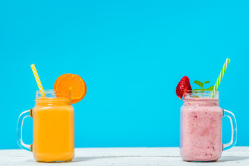 Refreshing summer smoothie with fruits and milk cocktail in jar on blue background, healthy breakfast