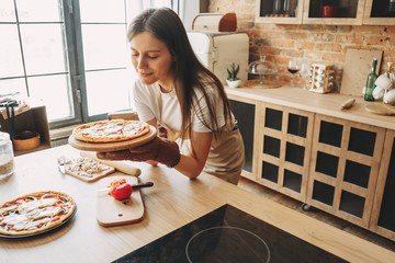 Young woman housewife baking pizza for her family at kitchen. Cooking with love, homemade recipe, culinary, food preparing concept