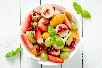 Fresh fruit salad on white wooden background