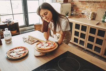 Young woman baking delicious pizza to her family and friends. Cooking with love, homemade recipe,...