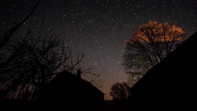 Timelapse of stars over timber house at night. 