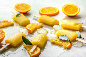 Orange popsicles with frozen juice and ice cubes, summer refreshing snack