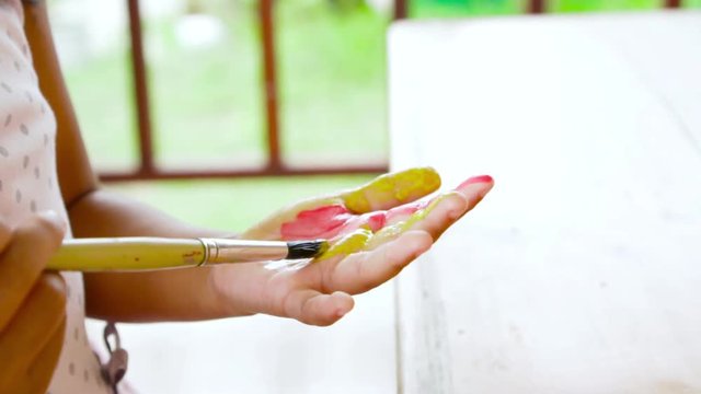 Asian childhood painting her hand in slow motion. Child crafts in leisure time.