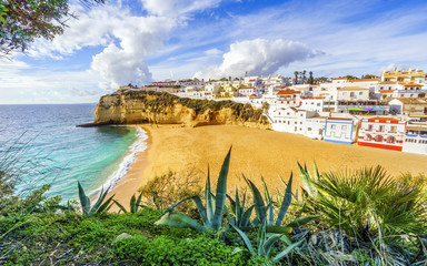 Sandy beach next to cliffs and white architecture in Carvoeiro, Algarve, Portugal
