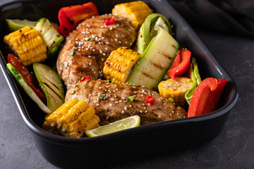 Chicken grilled fillet with vegetables on a black background.