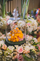 Met khanun, Thong yip and Thong yot on banana leaf. Traditional Thai dessert sweet variety in transparent glass cover and flower decoration background. Set up in Thai wedding ceremony. Select focus