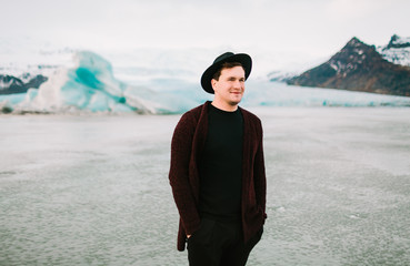 Young man in dark hat and casual clothes on glaciers background.