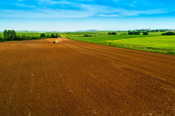 Fototapeta na wymiar Aerial shot of Farmer with a tractor on the agricultural field sowing.