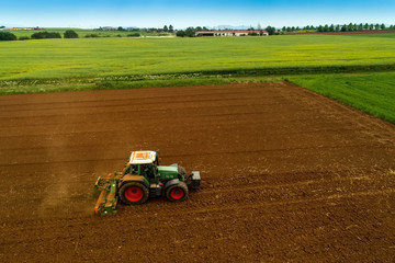 Obraz premium Aerial shot of Farmer with a tractor on the agricultural field sowing.