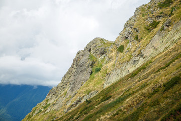 Photo of mountain slopes with vegetation and cloudy sky