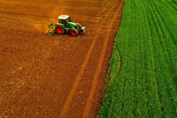 Aerial shot of  Farmer with a tractor on the agricultural field sowing.