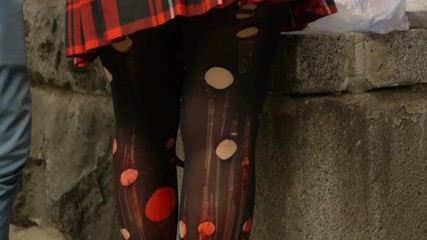 The girl in a short red skirt and torn pantyhose, nylon tights in holes