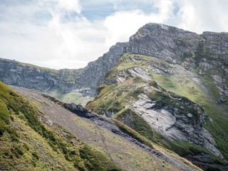 Photo of mountain slopes with vegetation and cloudy sky