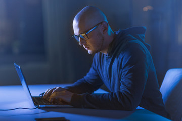 cybercrime, hacking and technology crime - male hacker in dark room writing code or using computer...