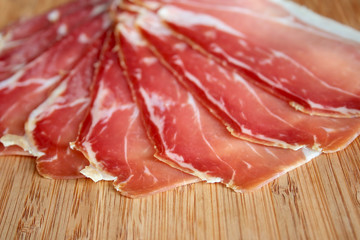 Sliced prosciutto on wooden board

