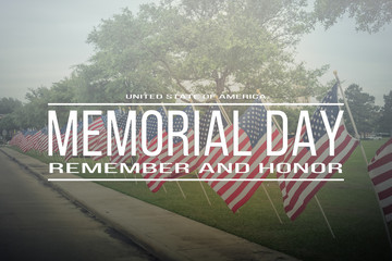 Text Memorial Day remember and honor on long row of lawn American Flags background. Green grass...