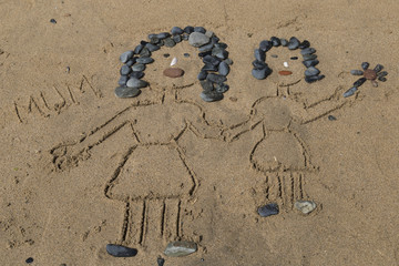 drawing a picture with stones of mother's day on sand on the beach.