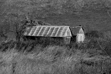 Black and white photo of a two old and derelict out buildings