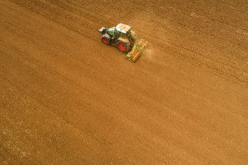 Aerial shot of  Farmer with a tractor on the agricultural field sowing.