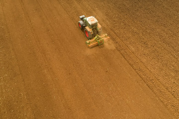 Aerial shot of  Farmer with a tractor on the agricultural field sowing.