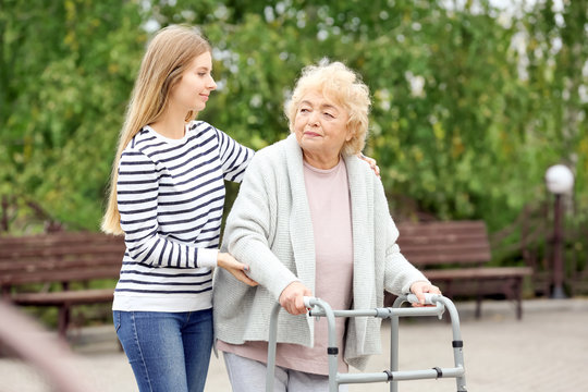 Young woman and her elderly grandmother with walking frame outdoors