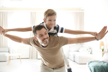 Cute little boy and father playing together at home