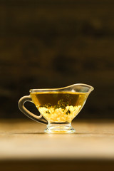 Transparrent  gravyboat with extra virgin olive oil and garlic on the wooden table  and black background