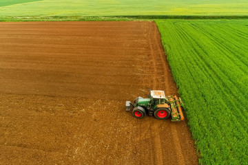 Fototapeta premium Aerial shot of Farmer with a tractor on the agricultural field sowing.