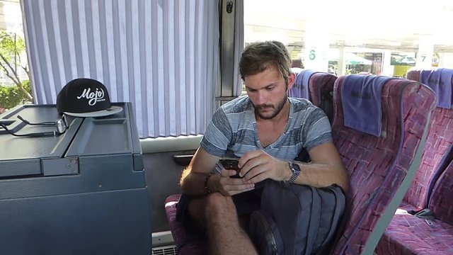 "Young man texting on a smartphone in a bus