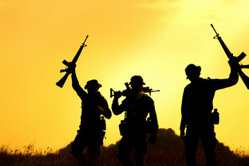 Fototapeta na wymiar Silhouette of military soldier holding weapons overhead after get victory of war at sunset.