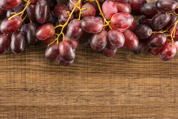 Red globe grapes table top isolated on brown wood background shiny deep pink berries.