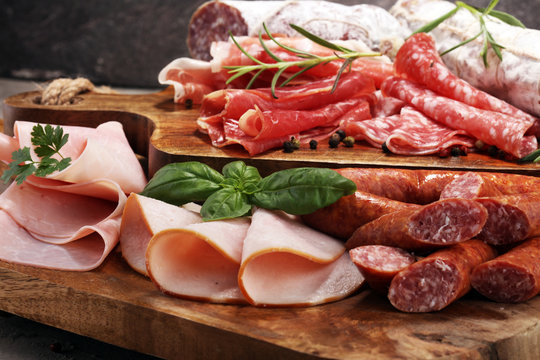 Food tray with delicious salami, ham,  fresh sausages and herbs. Meat platter with selection