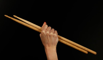 Close up woman hand with drumsticks over black