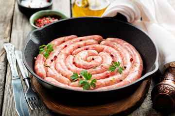 Raw sausage of beef and pork with spices on dark wooden background. 