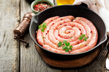 Raw sausage of beef and pork with spices on dark wooden background. 