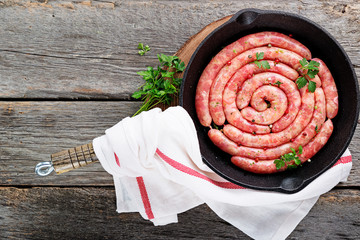Raw sausage of beef and pork with spices on dark wooden background. top view.