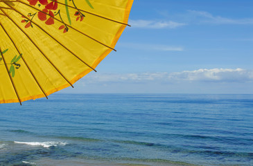 Yellow sunshade against blue sea and sky