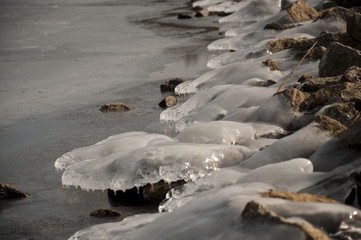 Ice little hills on the rocky beach of the melting german lake. Makes shape of waves.