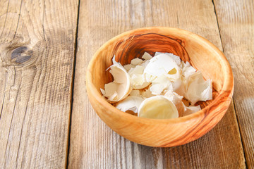 Fototapeta na wymiar Boiled chicken eggs and their shells in wooden bowls on an old wooden table.