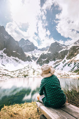 Boy traveler rests near beautiful mountain lake. Spring summer hiking, active leisure concept image
